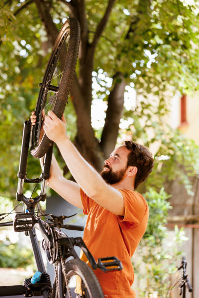 istock Man reattaching bicycle wheel in yard 1584684316