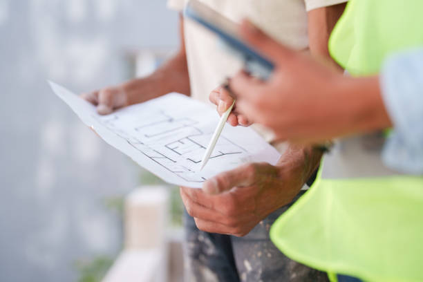 istock Female engineer and foreman looking at blueprints at the construction site. 1584699064