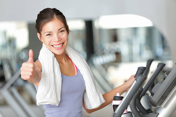 feliz fitness mujer pulgares arriba en gimnasio - gym machine smiling coach fotografías e imágenes de stock