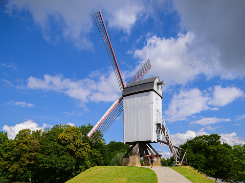 Bruges, Belgium - July 3, 2022: A windmill standing on a hill in bruges, sunlight, europe