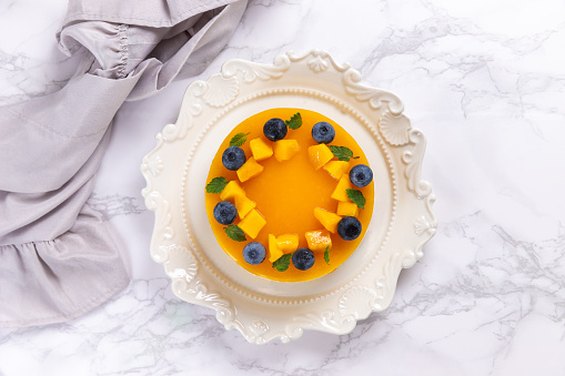 Homemade mango cheesecake garnished with pieces of ripe mango and blueberry