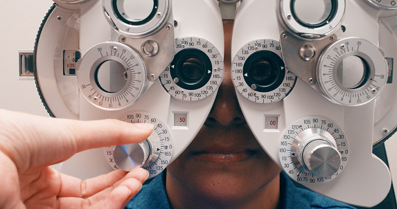 Ophthalmologist hands, phoropter and person with eye exam for vision, wellness and healthcare. Optometry, eyesight test and patient with medical doctor for consultation, inspection and lens closeup