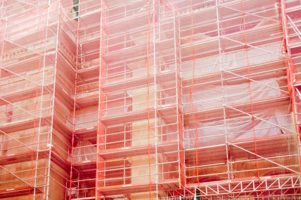Detail of scaffolding and red netting on an apartment building construction site . Full frame view.