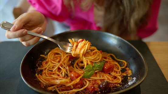 Woman eating italian pasta with basil tomatoes and olives