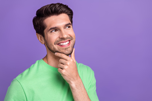 Portrait photo of young thoughtful guy touch chin looking empty space minded virile unshaved bristle isolated on violet color background.