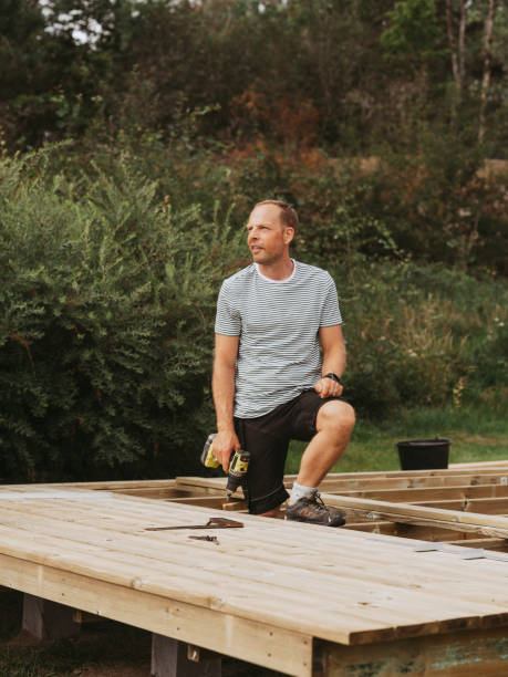 istock Man building a wooden patio deck outdoors in his garden 1584782982
