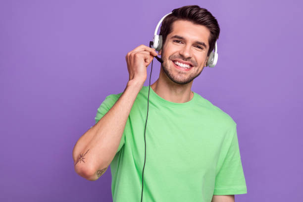 istock Portrait of young optimistic man customer client support helpline headset touch microphone telemarketing isolated on purple background 1584783539