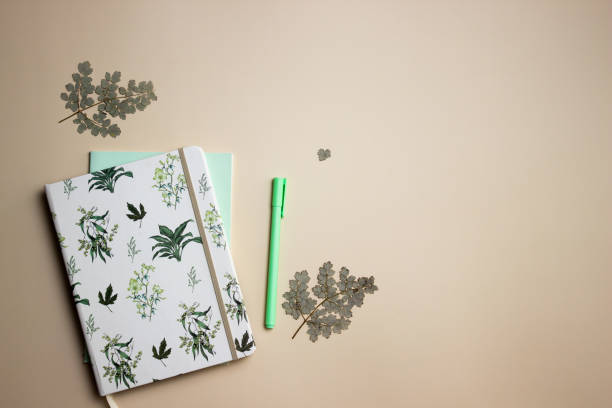 istock Diary concept with green pen and leaves on a brown background. 1584785176