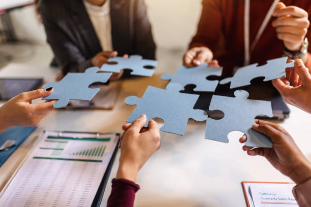 istock Group of professional people playing puzzle in the office. 1584791100