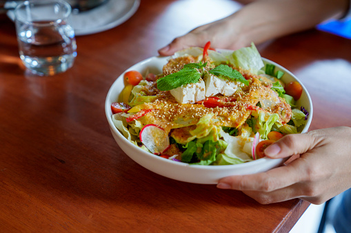 A young Asian woman holding a bowl of mixed salad as a part of her healthy lifestyle