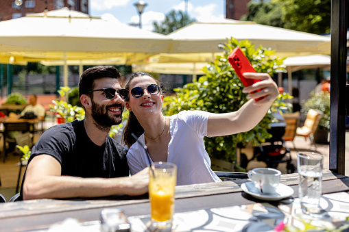 Striking a romantic pose, the couple captures a picture-perfect selfie, their love radiating amidst the serene surroundings of the charming cafe garden