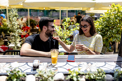 Sharing a table for two, the couple creates lasting memories as they immerse themselves in the delightful haven of the cafe garden, savoring delicious treats, engaging in intimate conversations, and relishing the beauty of their togetherness