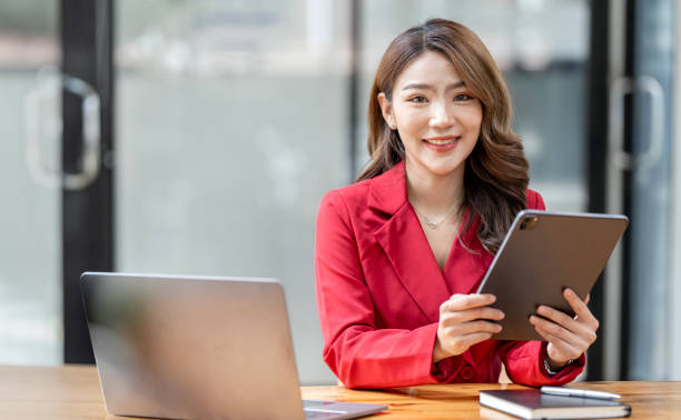 istock Young female entrepreneur working on a tablet and laptop in a modern workspace. 1584828769