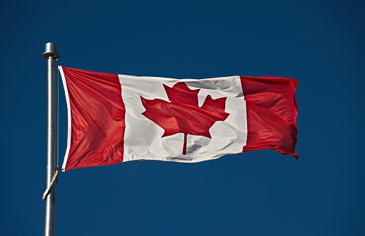 A Canadian flag with aMt. Noruay of the Canadian Rocky Mountains in the background.