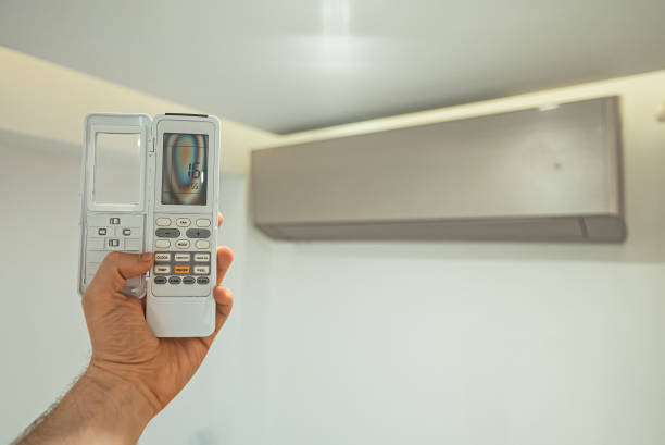 istock Hand holding remote control in front of the air conditioner. 1584848008