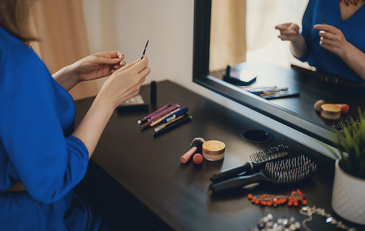 Woman doing makeup in front of a mirror at home.