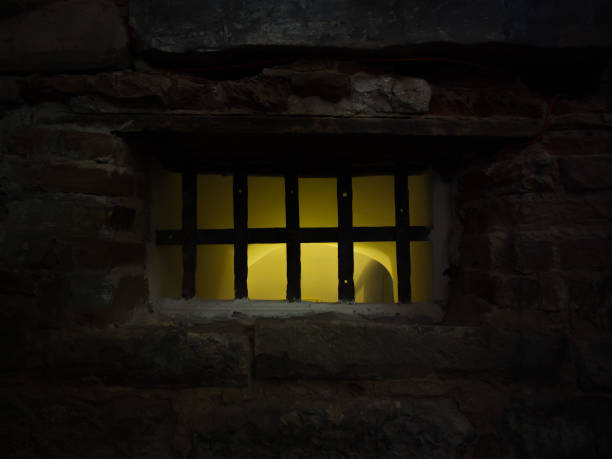a janela barrada da masmorra foi iluminada com luz amarela - prison cell prison prison cell door crime - fotografias e filmes do acervo