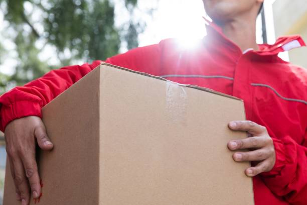 istock man in red with box outside house waiting for delivery order 1584936707
