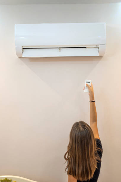 istock Beautiful girl turning on air conditioner 1584950528