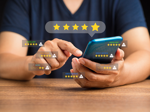 Customer service and satisfaction surveys concept. Man using a smartphone give the five-star icon a rating of very impressed for service. Close-up photo