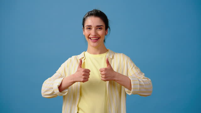 Positive woman expresses approval showing thumbs up