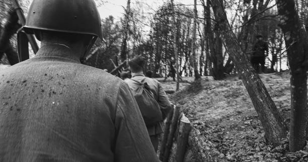 istock Re-enactors Dressed As Soviet Russian Soldiers take up fighting positions in trenches. Position Defense. Soldiers Aiming With Rifles. Reconstruction Of Battles World War Ii. Black And White 1584963899
