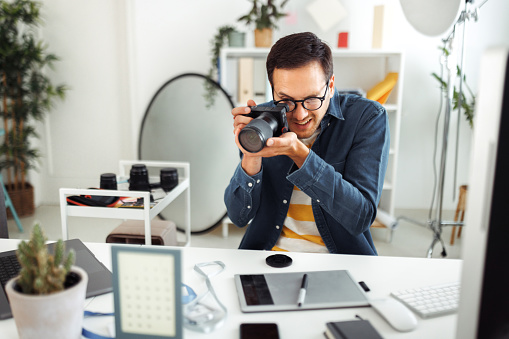 Casually clothed handsome photographer working at home office