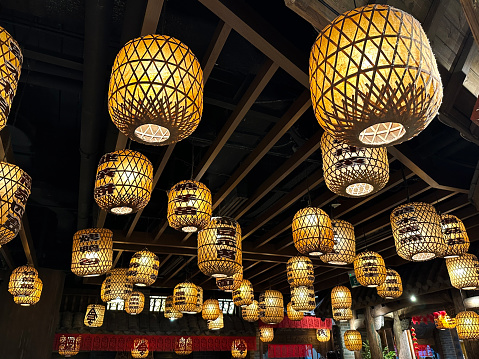 Stock photo showing illuminated Chinese style bamboo and paper lanterns suspended from ceiling.