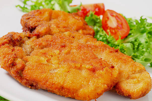 Wiener schnitzel (escalope) big fried breaded Wiener schnitzel (escalope) with vegetable garnish on a white plate schnitzel stock pictures, royalty-free photos & images