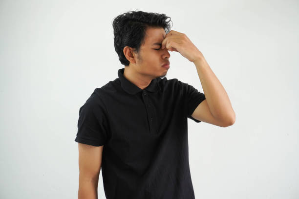 casual young asian man against a vibrant white studio background, having a head ache, touching front of the face, wearing black polo t shirt - pusing imagens e fotografias de stock