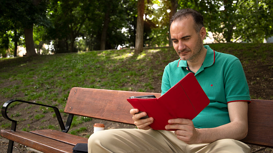 man sitting in the park reading with tablet