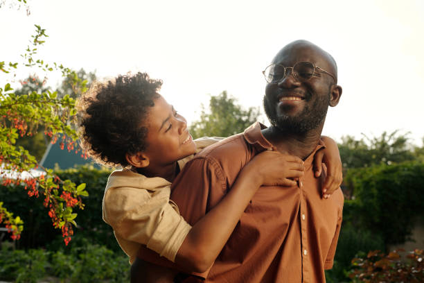 istock Happy cute African American boy embracing his father behind back 1585015712