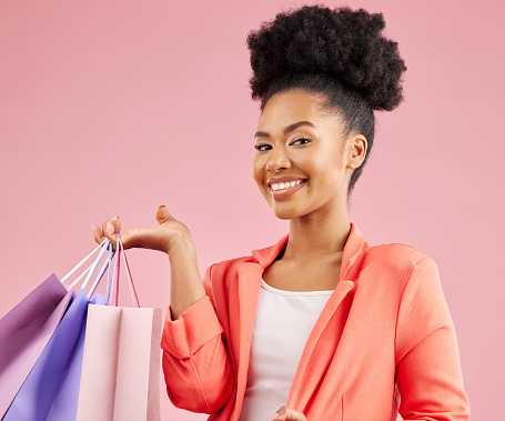 Happy African woman, shopping bag and studio portrait for discount, sale or smile by pink background. Young gen z girl, promotion and excited for deal, retail customer experience or fashion for gift