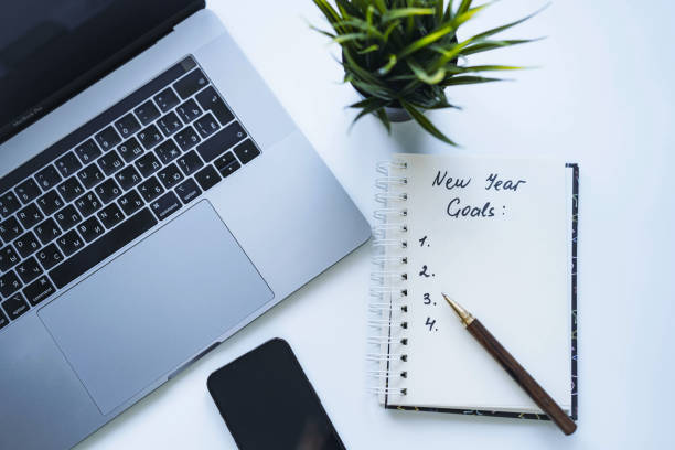 istock open notepad with text new year resolutions and empty list. laptop and smartphone on background 1585057327