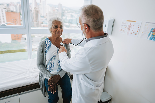 Portrait of a doctor listening to an elderly woman patient's heartbeat