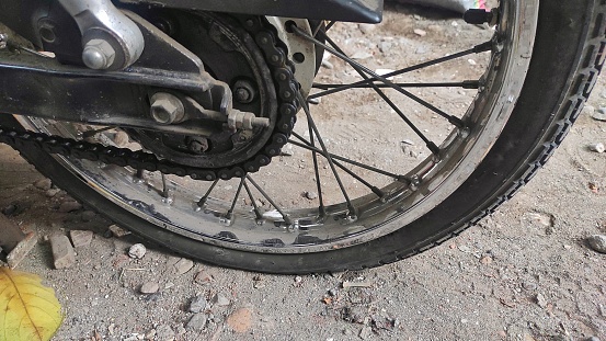 Flat tire of motorcycle on the dirt street in urban area