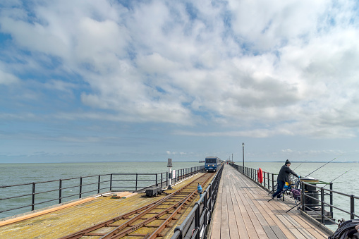 man wearing waders repairing pier in a lake with a cloudy sky.