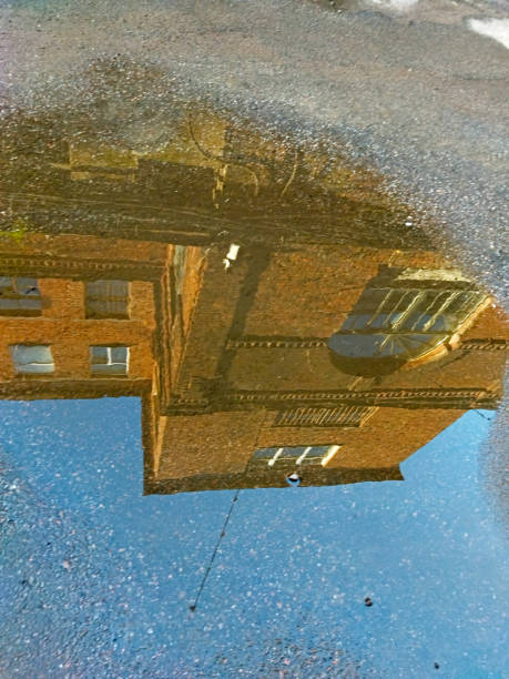 istock Vintage red brick building and blue sky reflected in water on a sunny day. 1585094928