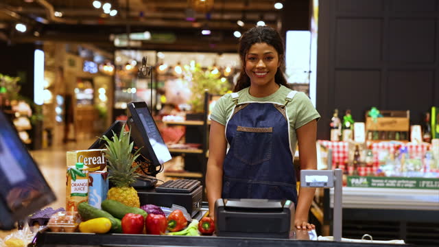 Video portrait of beautiful black cashier facing the camera smiling very cheerfully