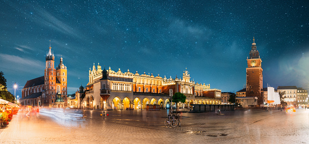 Krakow, Poland. Famous Landmarks On Old Town Square In Summer Evening. St. Mary's Basilica, Cloth Hall Building And Old Town Hall Tower In Night Lighting. UNESCO World Heritage Site. Panoramic View.
