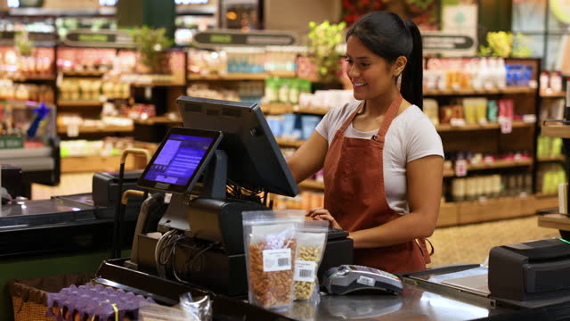 Beautiful cashier working at the supermarket checking something on system