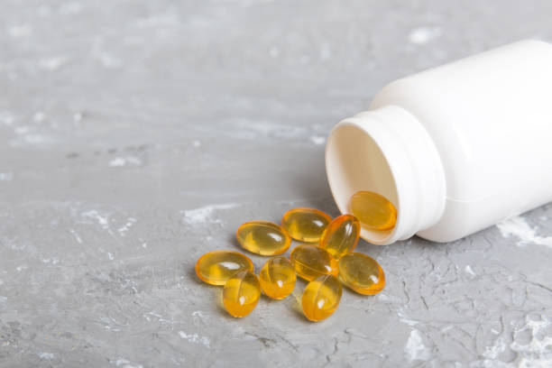 Omega-3 capsules lie in white bottle on a table background. Fish oil tablets top view. Biologically active additives. omega 6, omega 9, vitamin A, E, vitamin D, vitamin D3, evening primrose oil. las cápsulas de omega-3 se encuentran en una botella blanca sobre un fondo de mesa. tabletas de aceite de pescado vista superior. aditivos biológicamente activos. omega 6, omega 9, vitamina a, e, vitamina d, vitamina d3, aceite de onagra