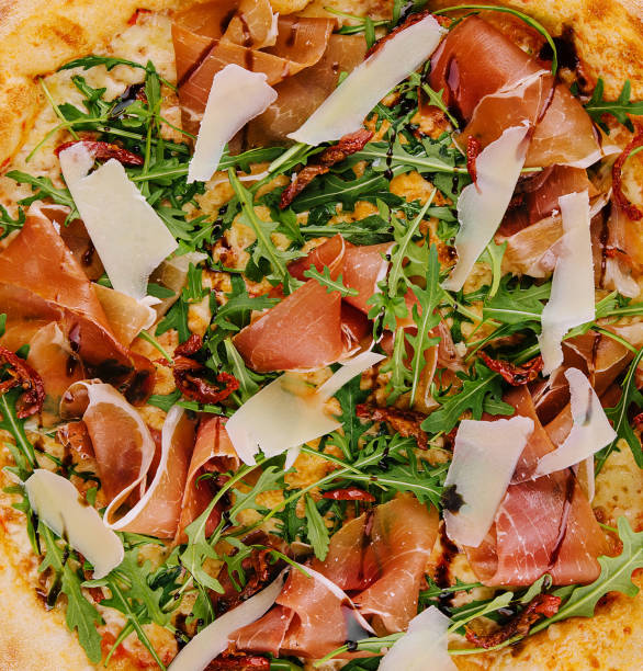 istock pizza with prosciutto (parma ham), arugula (salad rocket) and parmesan 1585149340