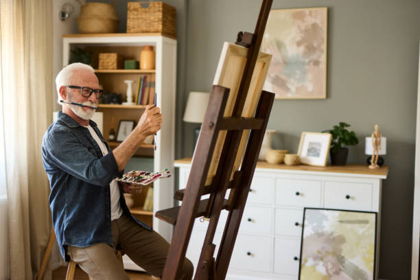 istock Elderly man painting on a canvas at home 1585166141
