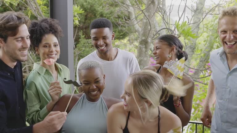 Smiling friends posing with photo booth accessories during a party together