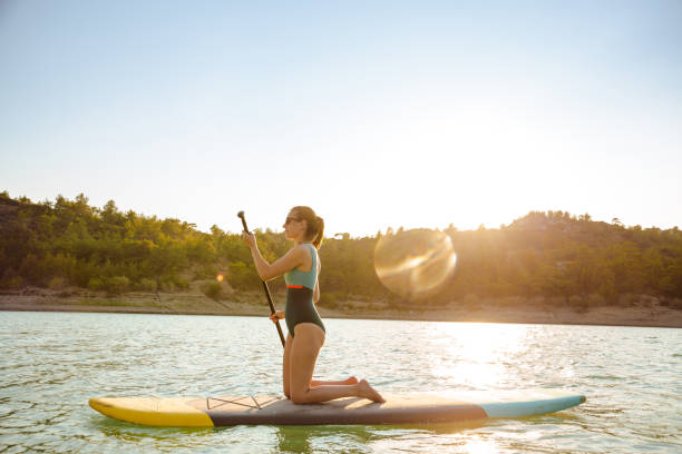 istock Young woman paddle boarding on the lake during summer 1585191848