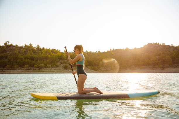 istock Young woman paddle boarding on the lake during summer 1585192403