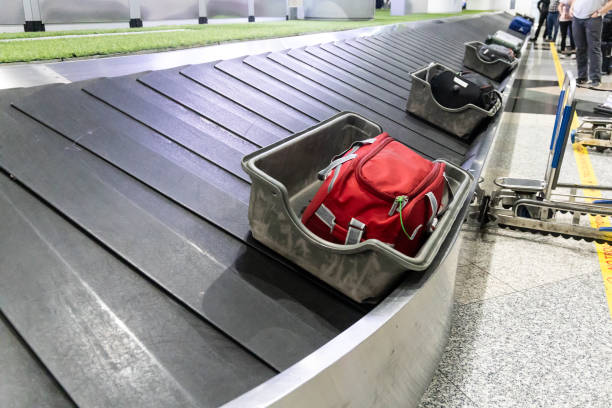 istock Soft and fragile bags are placed into protective containers before loaded onto conveyer belt at airport for passenger collection 1585204873
