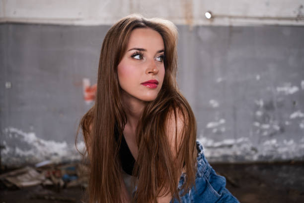 Fashion portrait of a beautiful young girl in denim dress on a background of a tree