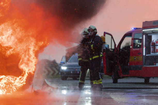 istock Firefighters using water fire extinguisher to fighting with the fire flame in car accident. Firefighter industrial and public safety concept rescue in night. 1585247557